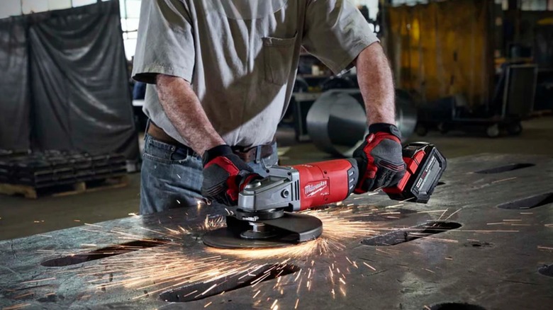 A person using a large Milwaukee angle grinder on metal.