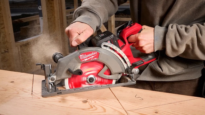 A person cutting wood with a Milwaukee rear handle circular saw.