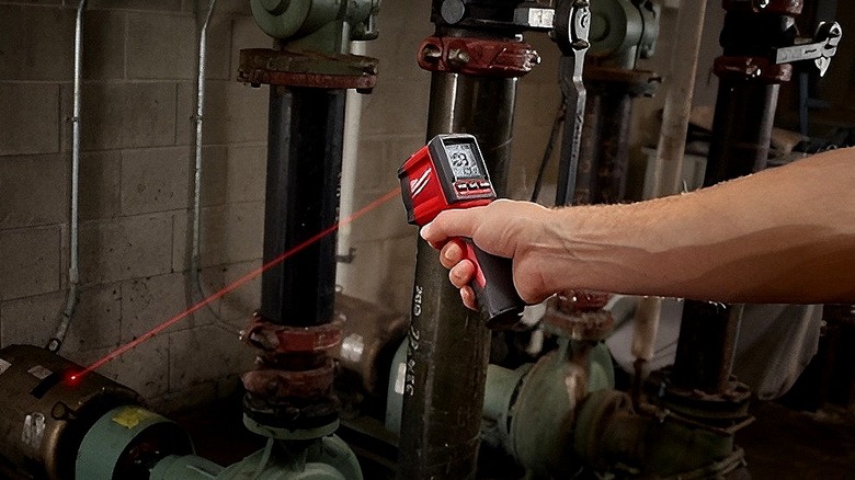 Milwaukee infrared temperature gun being pointed at pipes