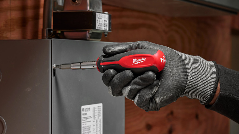 Using a Milwaukee 11-in-1 Screwdriver to open a metal box.