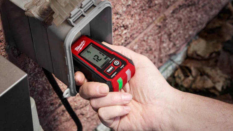 A person testing an outlet with a Milwaukee outlet tester.