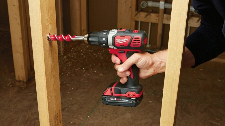 A person using a Milwaukee M18 drill on wood.