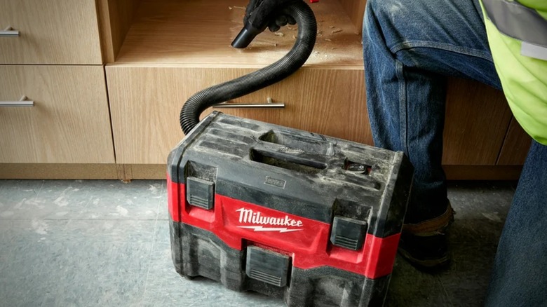 A person cleaning with a Milwaukee cordless wet/dry vacuum.