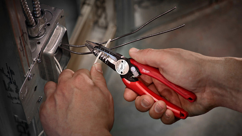 Hands stripping wire with Milwaukee Wire Stripper/Cutter Pliers.