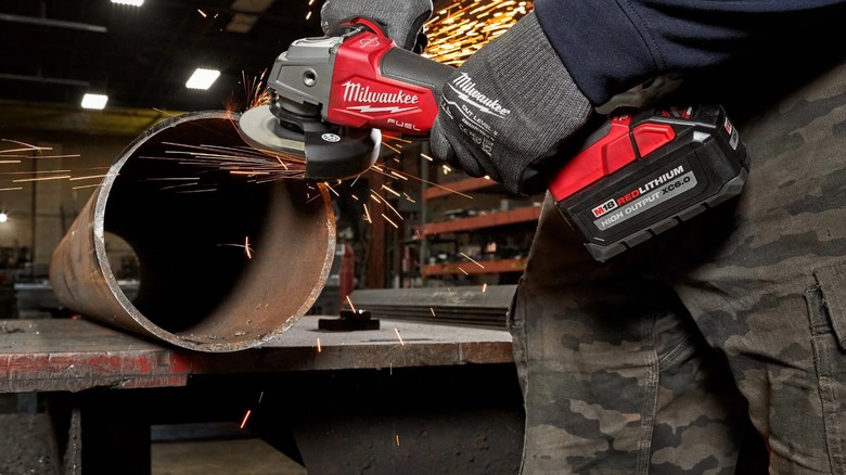 A worker preparing a pipe edge with a Milwaukee angle grinder