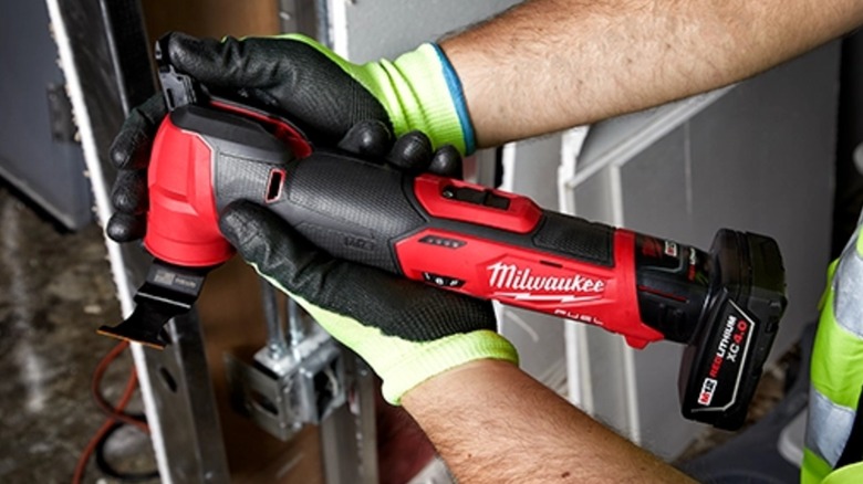 A worker holding a Milwaukee M12 Fuel multi-tool