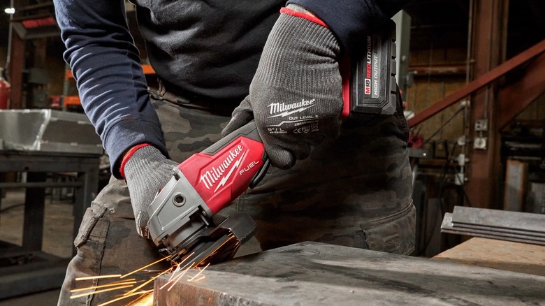 Worker preparing the edge of a metal surface with a Milwaukee M18 Fuel grinder