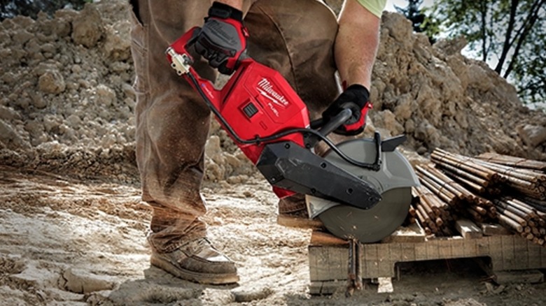 A worker cutting rebar with a Milwaukee cut-off saw at an outdoor worksite