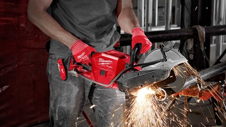 A worker cutting metal pipe with Milwaukee cut-off saw