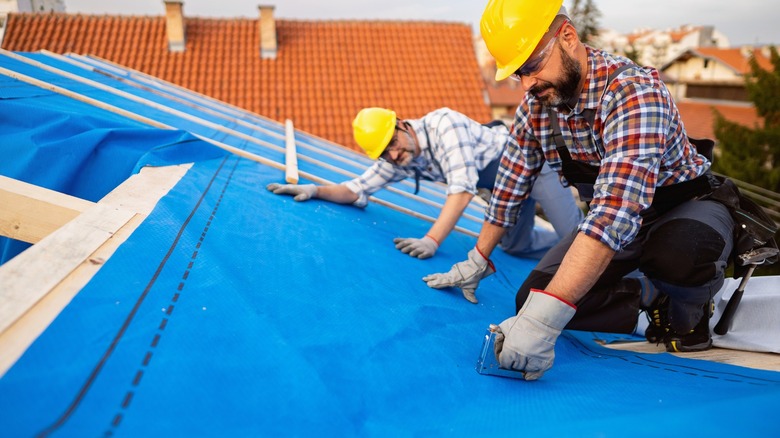 Two men installing roof felt paper