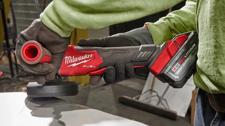 Person using Milwaukee angle grinder on table