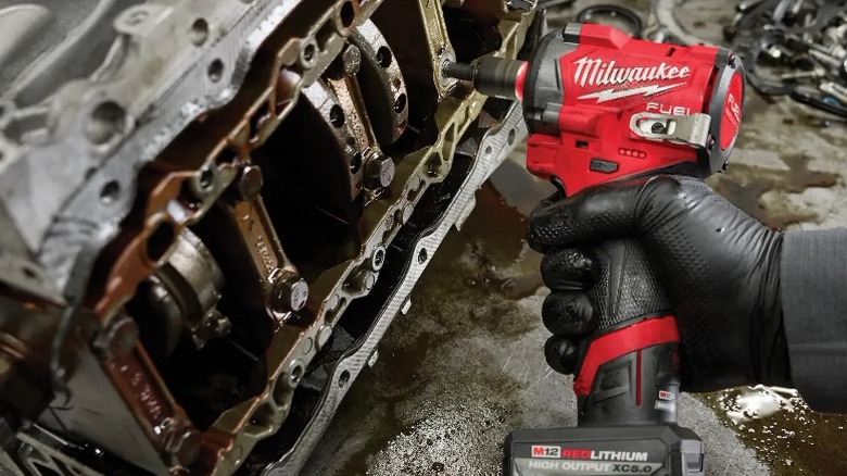 Person using Milwaukee M12 Stubby ⅜-inch Impact Wrench on engine