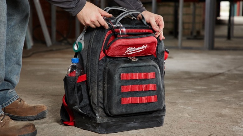 Person putting glasses in Milwaukee 15-inch Ultimate Jobsite Tool Backpack