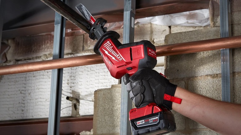 A person using a Milwaukee Hackzall on metal pipes.