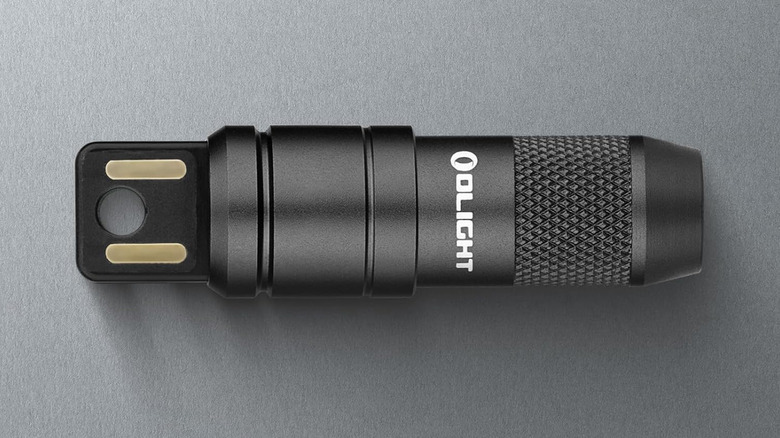 An Olight iMini 2 flashlight on a gray, textured table.