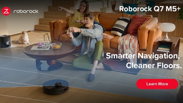 Roborock black Q7 M5+ robot vacuum in home with couple gaming on couch