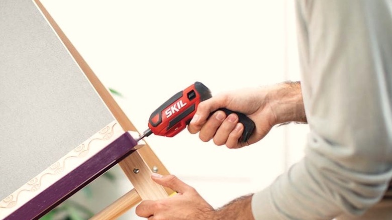 Person using a miniature Milwaukee screwdriver