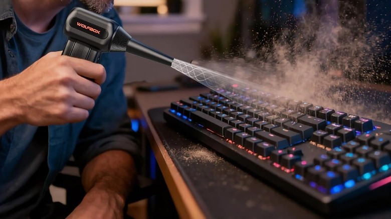 Man using a Wolfbox MF60 compressed air duster to clean a keyboard.