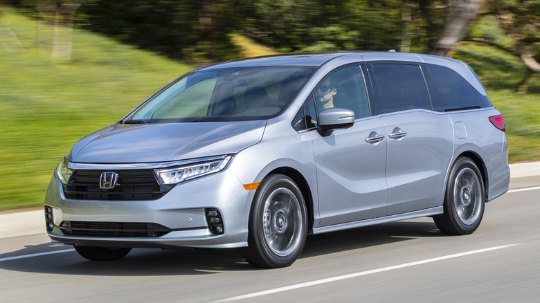 Front 3/4 view of silver Honda Odyssey driving on street.