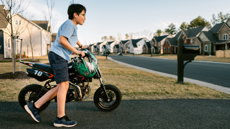 a kid walking with a small dirt bike