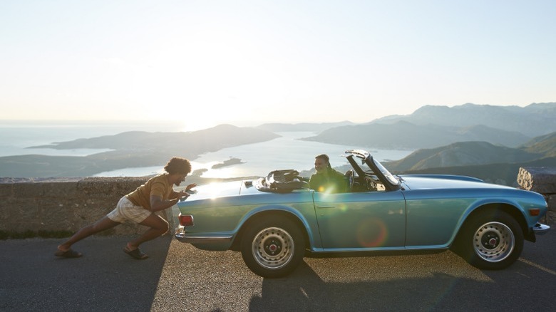 person with broken down classic car