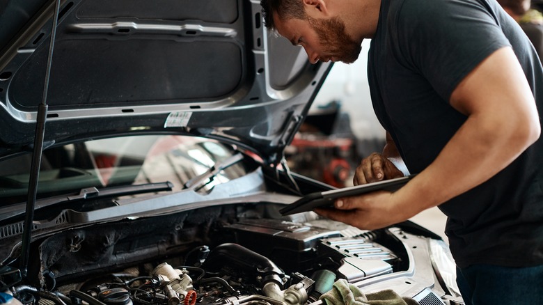 A mechanic inspects a car's engine.