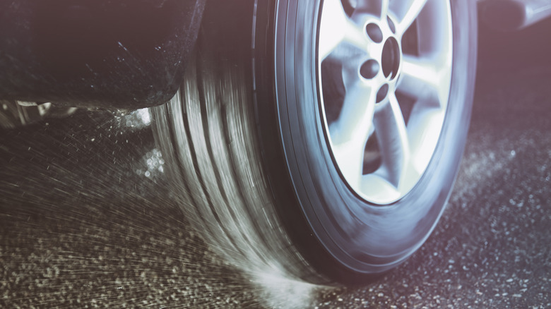 Spinning tire on wet asphalt during launch from standstill