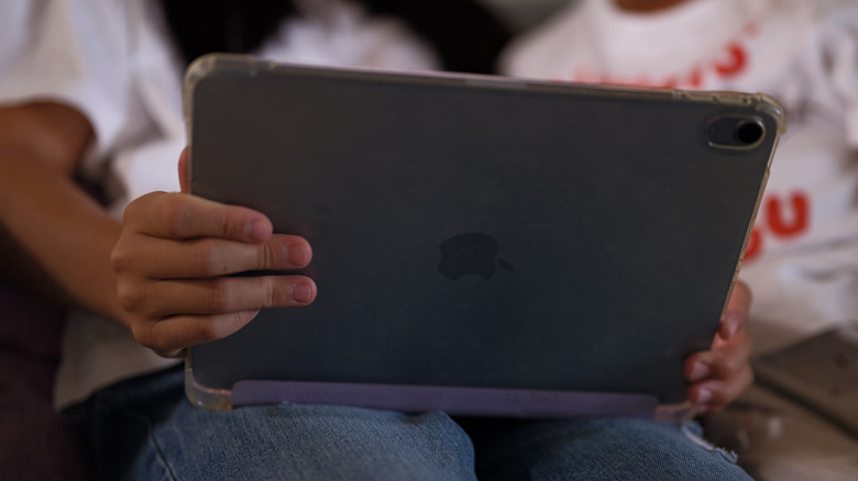 A person sitting on a couch with an iPad in their lap.
