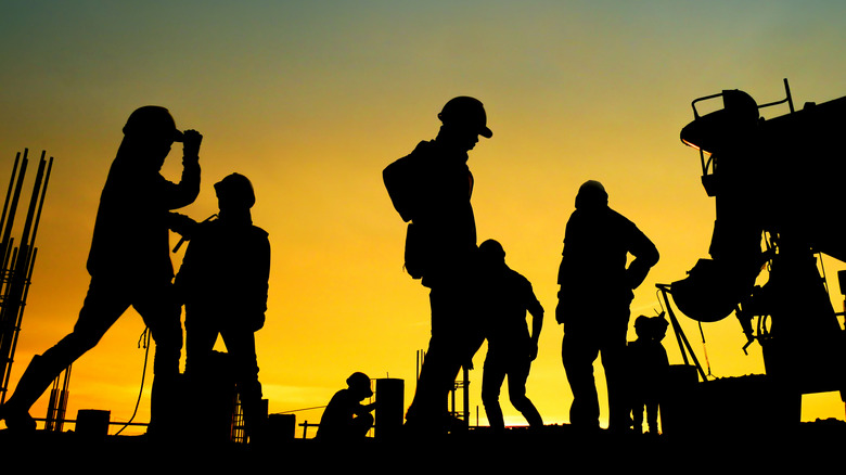 Construction workers working during sunset