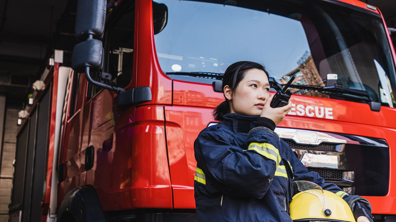 Firefighter standing outside truck speaking into walkie talkie