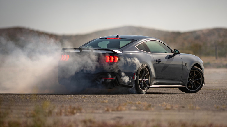 A Ford Mustang Dark Horse spinning its tires creating smoke