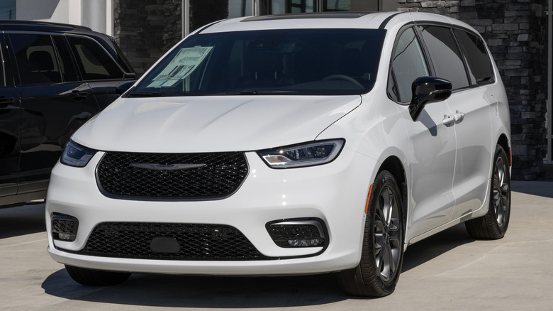 A white Chrysler Pacifica parked in front of a dealership.