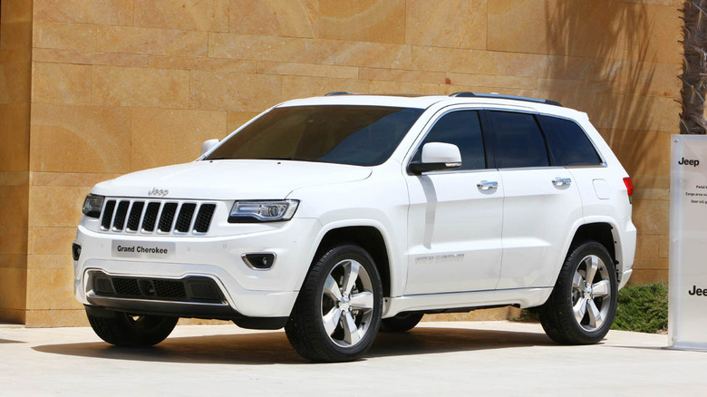 A white base-spec WK2 Jeep Grand Cherokee at a promo event, front 3/4 view