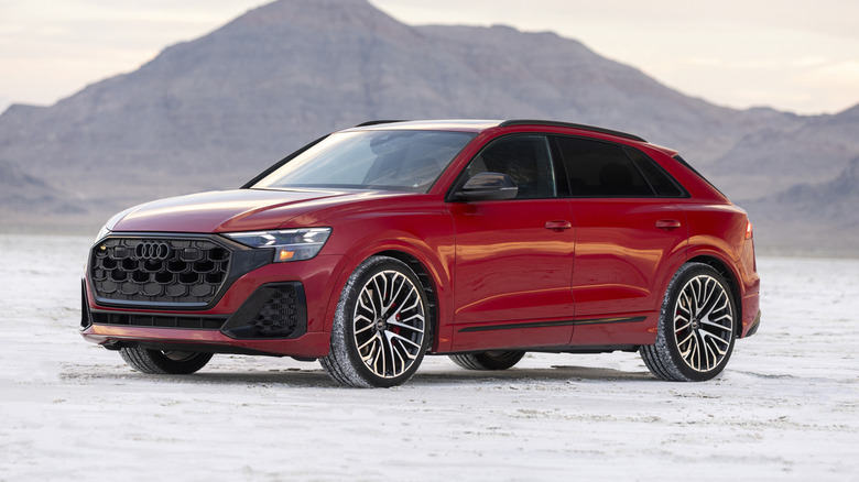 Red 2025 Audi SQ8 seen from left front parked on a slat flat with mountains behind