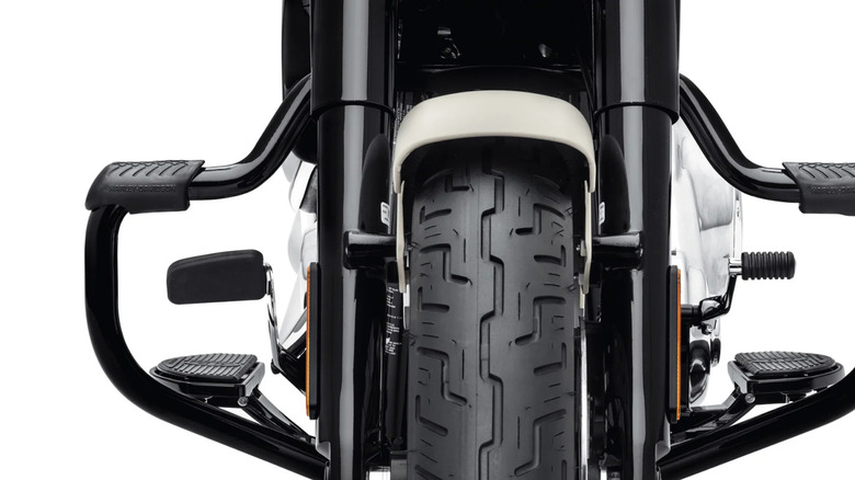 Front of a motorcycle wheel protected by a engine guard and footrests