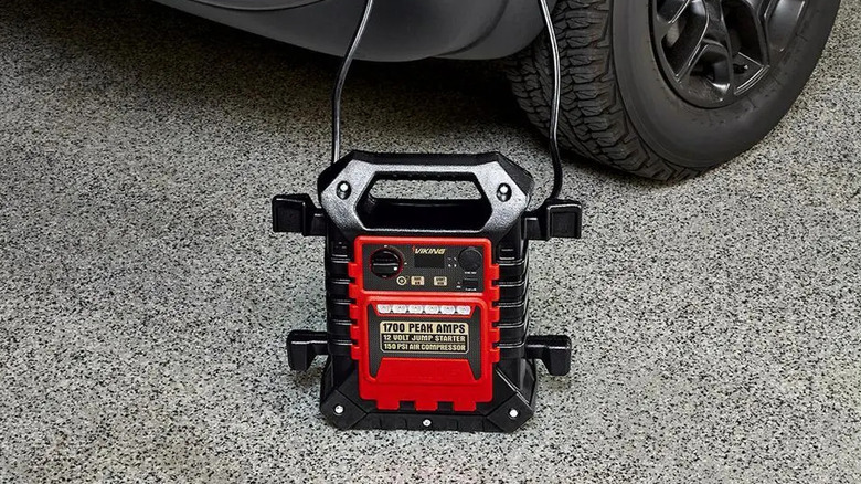 The Viking Jump Starter and Air Compressor on the floor, next to a black car