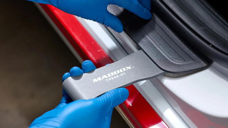 Mechanic using trim scraper to remove trim