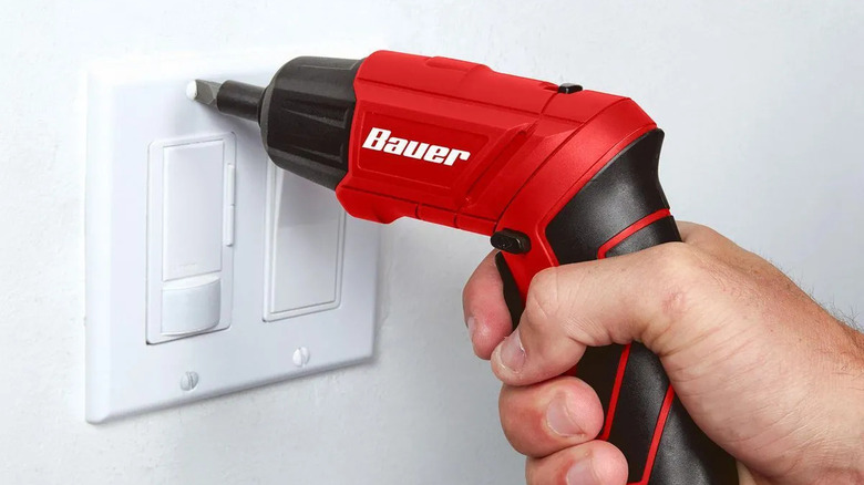 A Bauer Cordless Screwdriver being used to open a light swtich