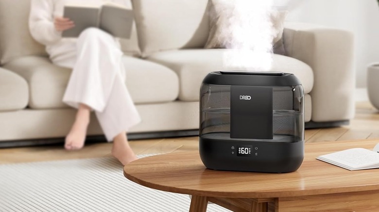 Dreo Humidifier being used in a living room with a person in the background reading