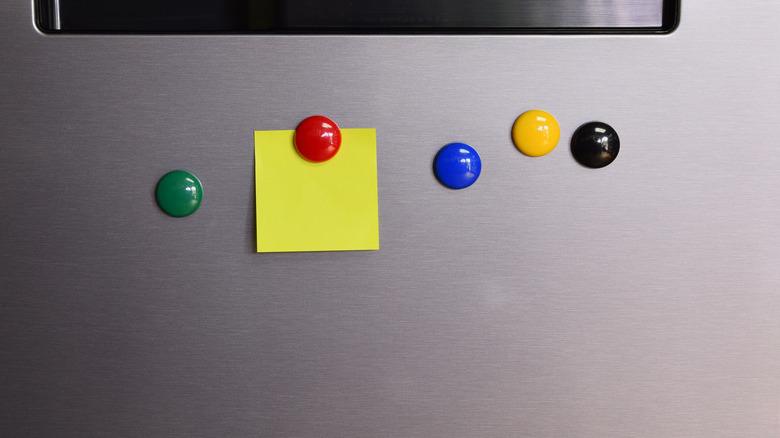 Colored magnets and a sticky note on the front of a refrigerator.