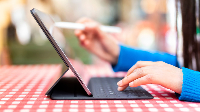 person using an iPad with a keyboard case on table
