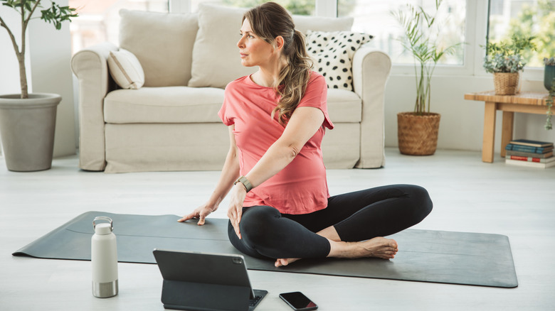woman sitting on yoga mat with iPad on the floor