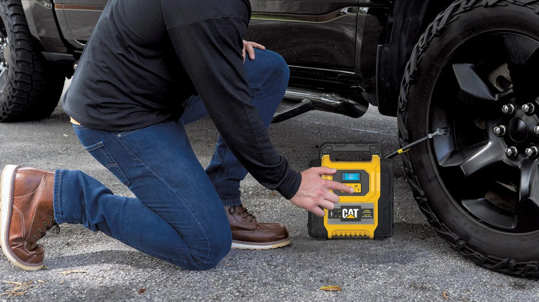 An air compressor by CAT being used to inflate a tire on a car