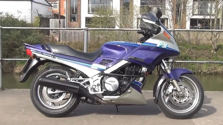 A 1985 blue Yamaha FJ1200 is parked outdoors near a river, blending retro sportbike looks with everyday road-ready practicality.