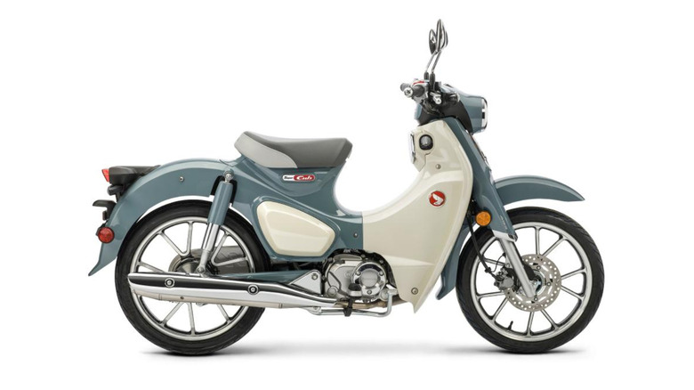 A pastel blue and cream Honda Super Cub with a step-through frame and chrome exhaust.