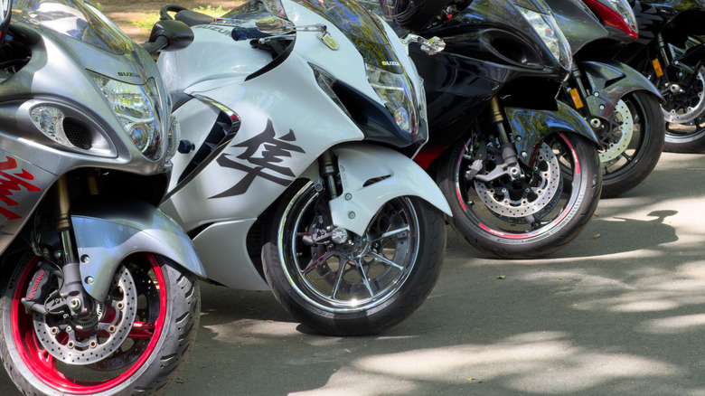 A row of parked motorcycles with the front of two Suzuki Hayabusas prominent in the foreground