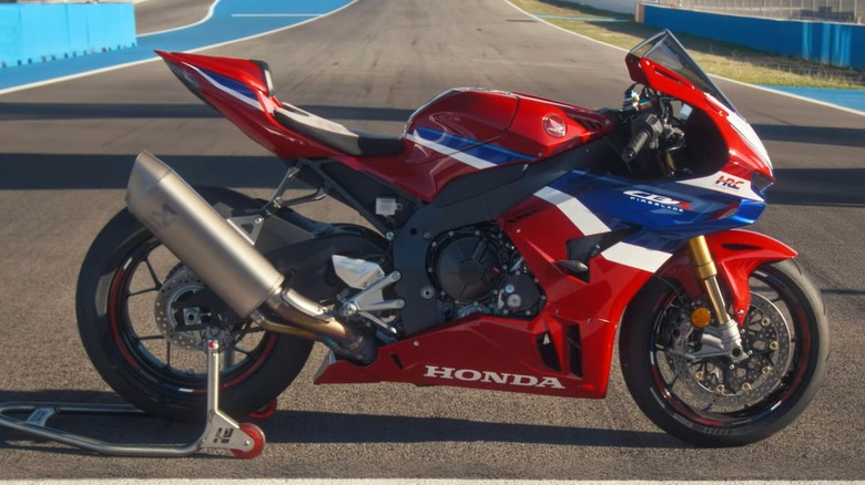 A 2024 red Honda CBR1000RR-R Fireblade SP mixed with a white and a blue color posed on a racetrack's start/finish line