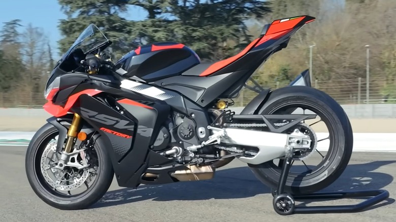 A black and red Aprilia 2026 RSV4 Factory 1100 parked on a racetrack on a rear paddock stand.