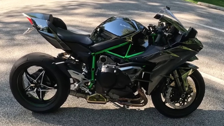A black Kawasaki Ninja H2 with its signature green trellis frame parked in a suburban parking lot.