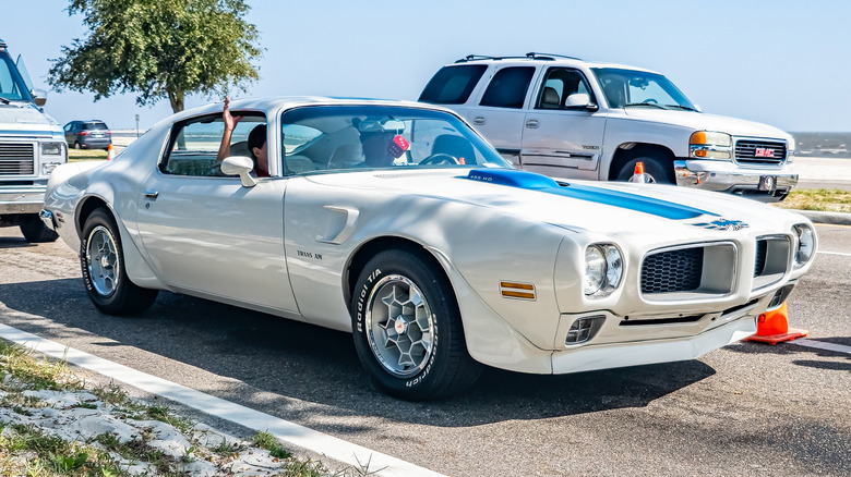 Front 3/4 view of white and blue early 1970s Pontiac Trans Am driving near beach.